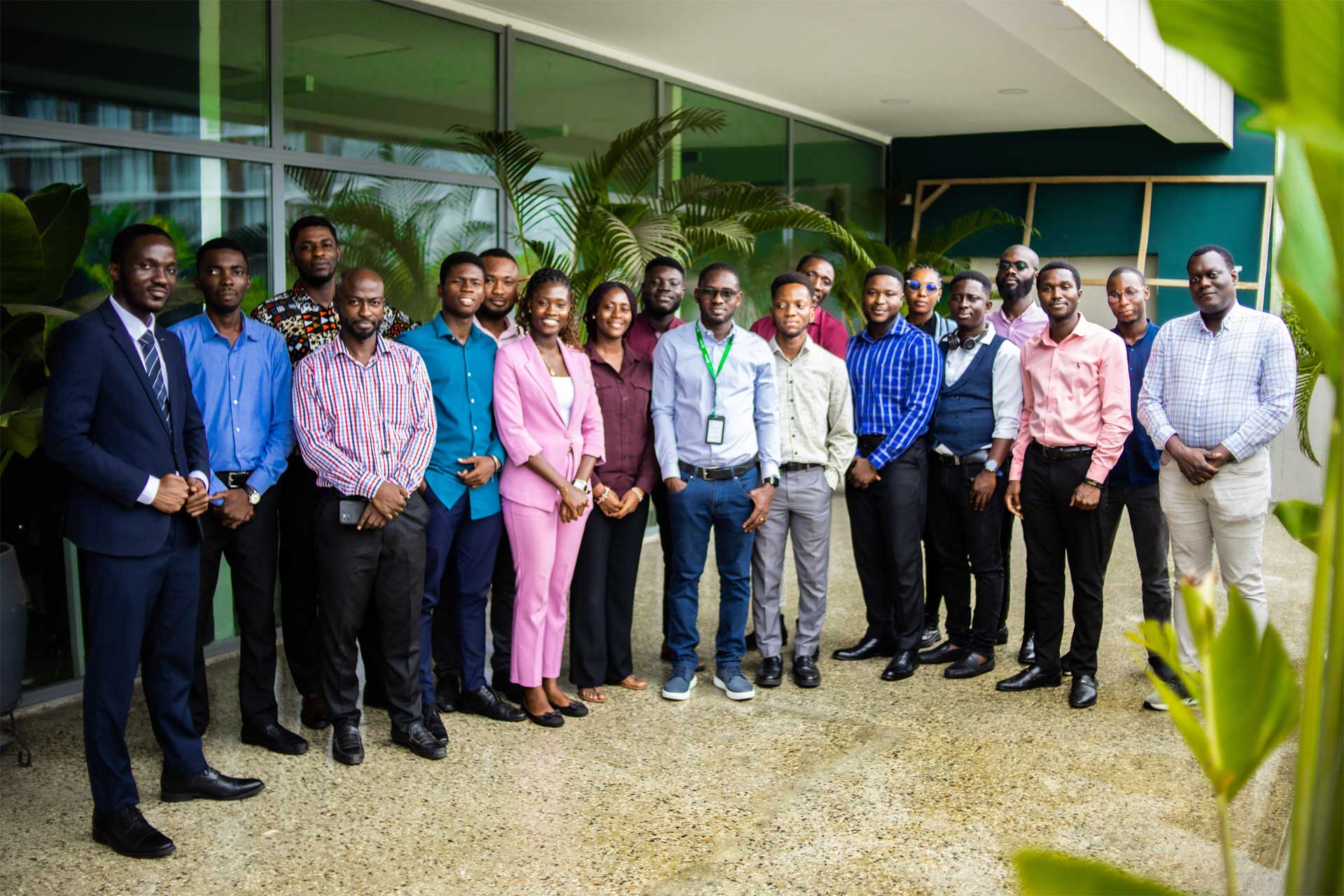 A group of individuals is standing in a line outdoors for a group photo.